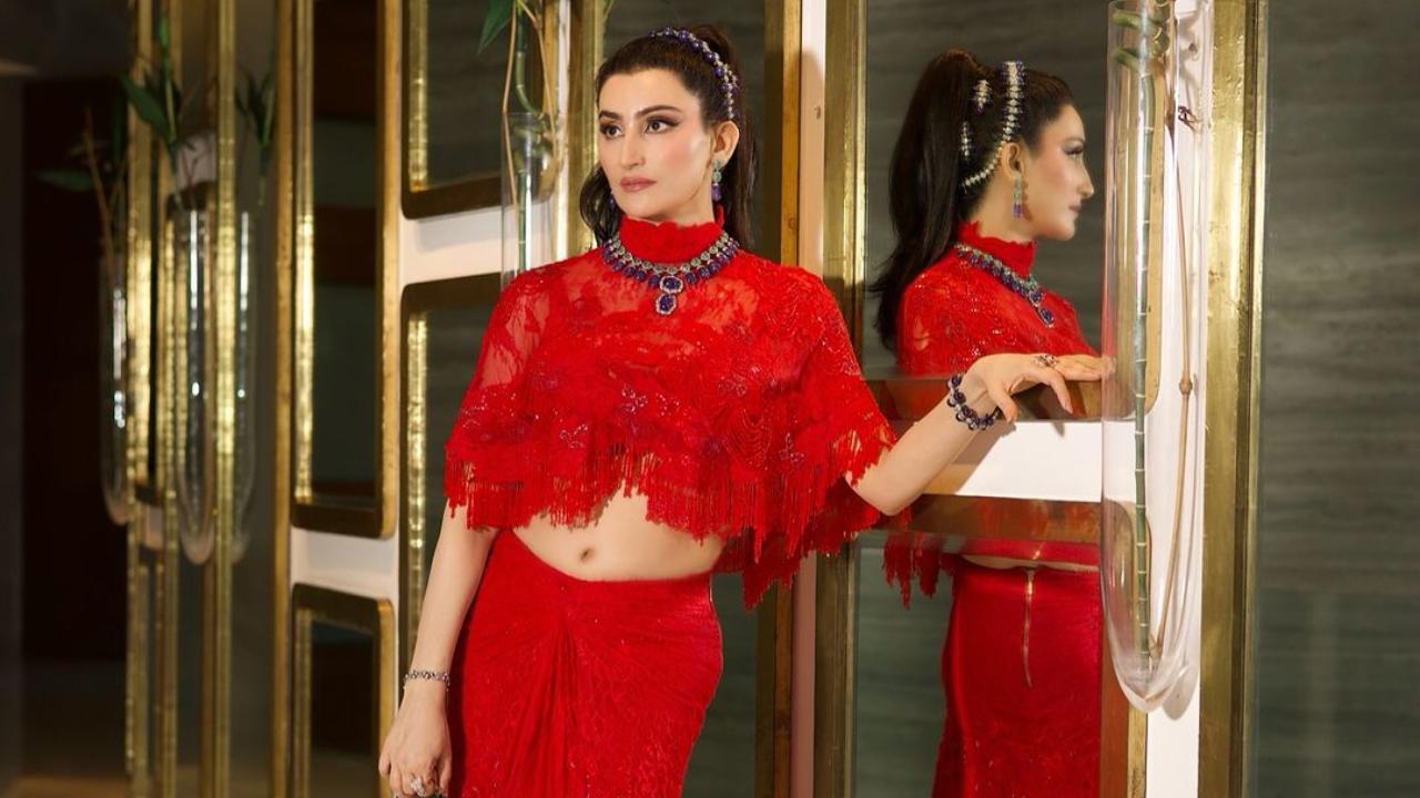 Here, she wears a vibrant red outfit, featuring a draped lace skirt, bralette and tulle cape. She completes her look with statement jewellery. 