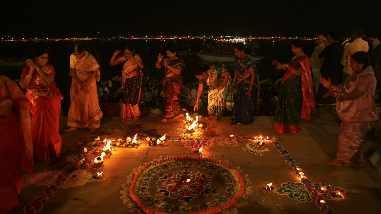 Devotees dance around the lit up earthen lamps as they celebrate Dev Deepawali on the banks of the river Ganges at Chauki Ghat in Varanasi