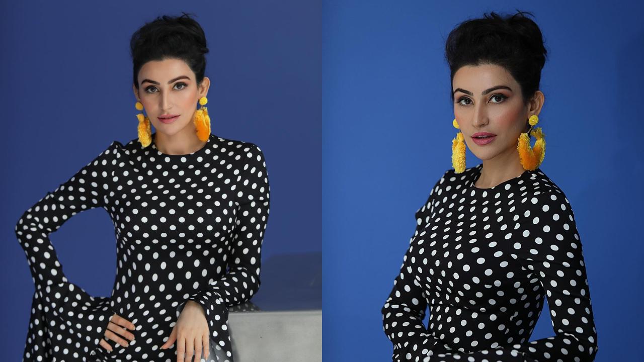 She opts for a classic black dress with white polka dots and pairs it with statement yellow hoop earrings. Her hairstyle lends the entire outfit a retro look. 