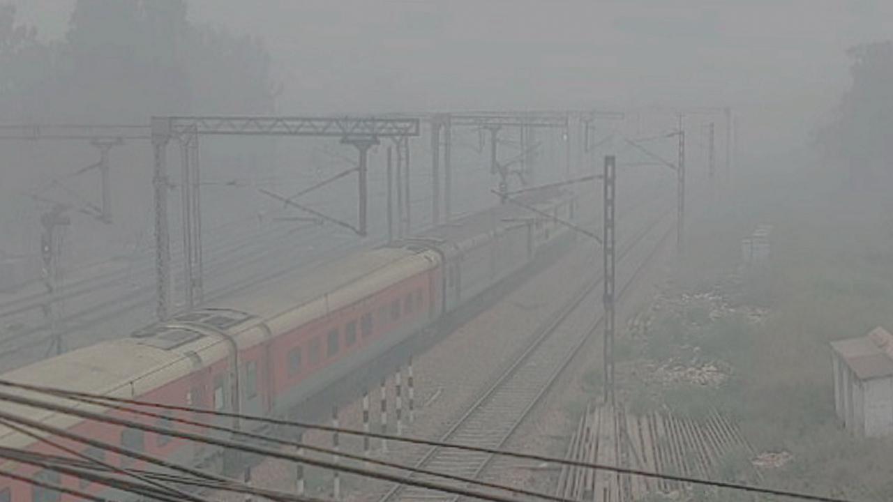 A train runs on its tracks amid low visibility due to smog near Patel Nagar