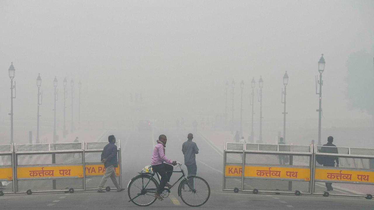A man cycles near the India Gate amid low visibility due to smog