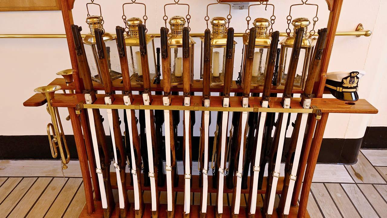 A view of the guns placed on the deck, with bugles and a cap