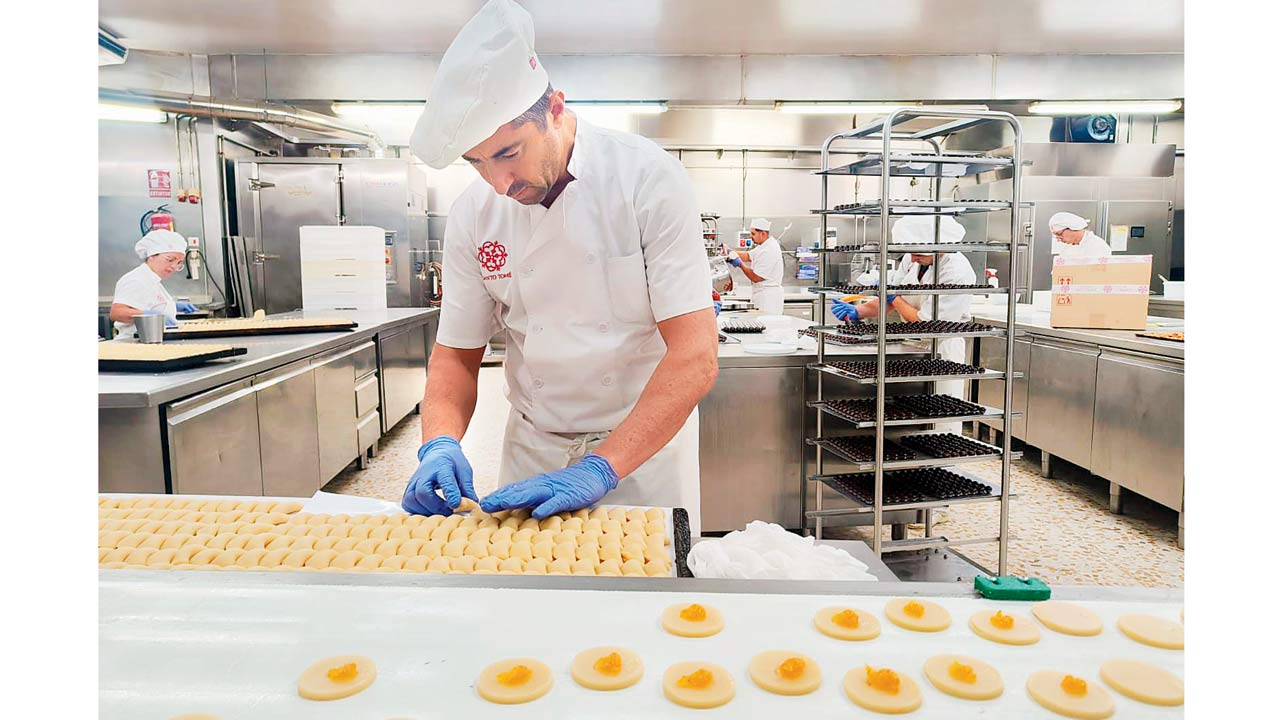 A worker readies trays of marzipan, coating them with egg before they are popped into the oven for three to four minutes