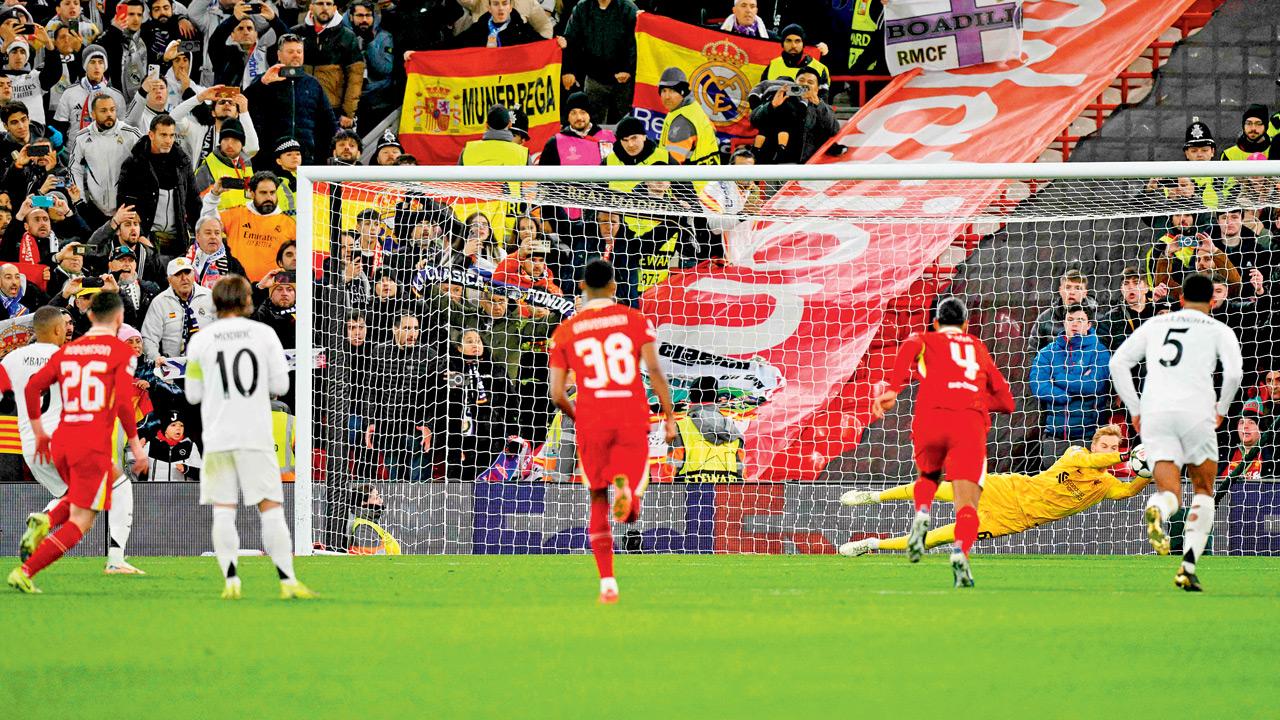 Liverpool goalkeeper Caoimhin Kelleher (yellow) dives to his left to save a penalty taken by Real Madrid’s Kylian Mbappe during their UEFA Champions League match at Anfield on Wednesday