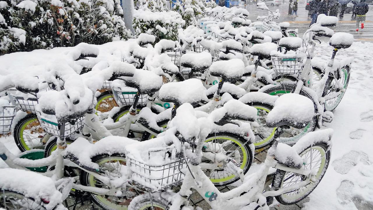 Snow-covered bicycles near a subway station