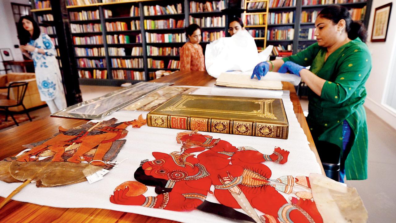 Members of the restoration team display rare books and artefacts (Tholu Bommalata shadow puppets) from their archive in the lab section