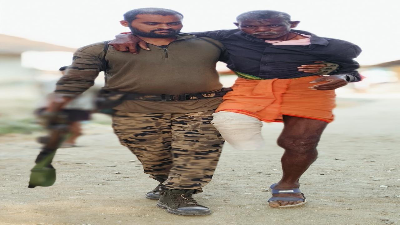 A paramilitary personnel posted in Gadchiroli assists an elderly man with crutches at the polling centre