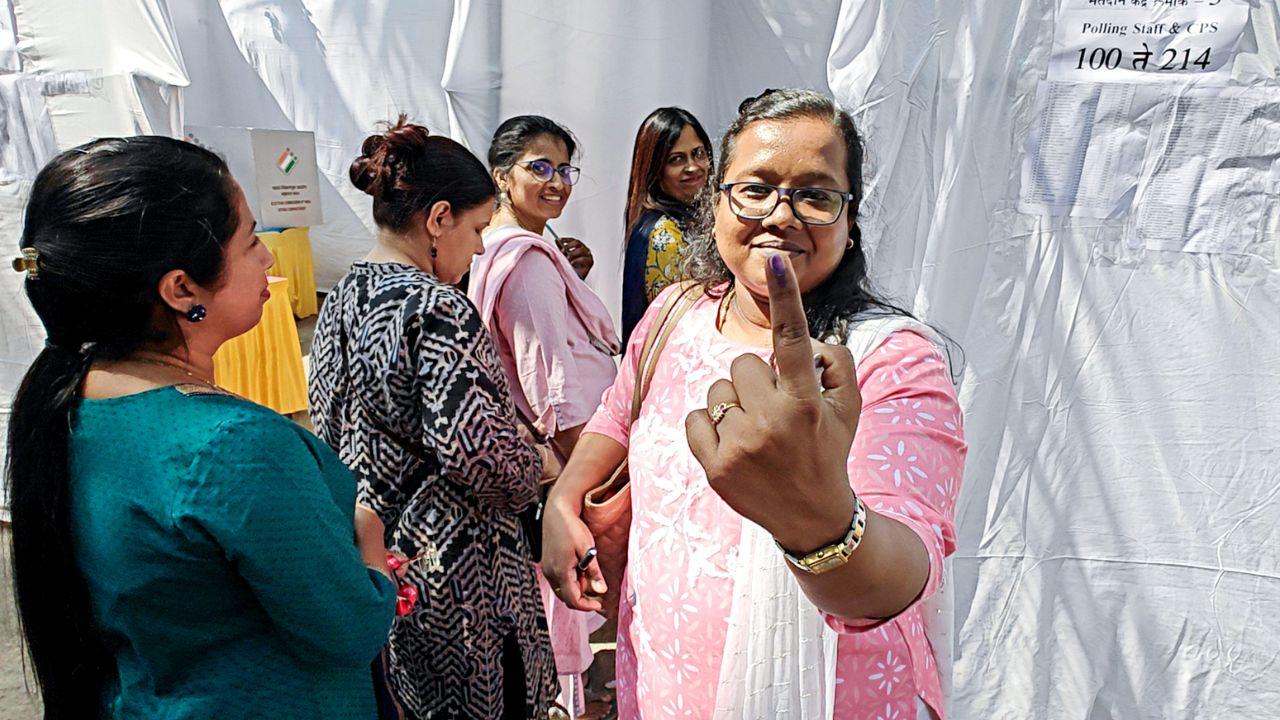 A polling official casts shows her ink-marked finger after casting her vote on the eve of Maharashtra Assembly elections, in Thane on Tuesday