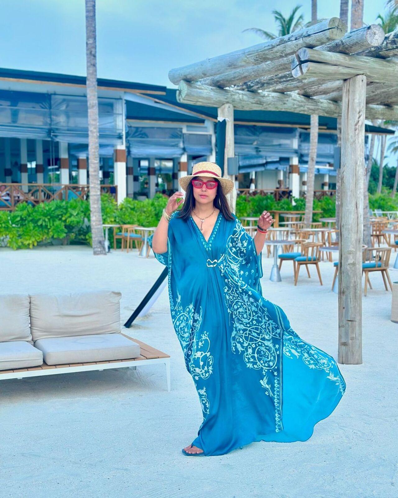 Hina dons a blue kaftan dress for a day out at the beach. She paired it with a red framed glasses and a beach hat