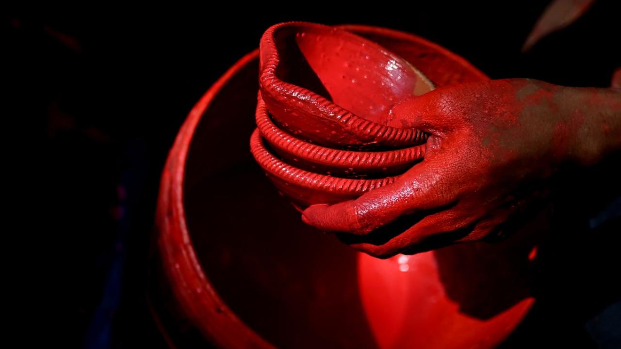 A potter paints diyas (earthen lamps) ahead of Diwali at his workshop in New Delhi