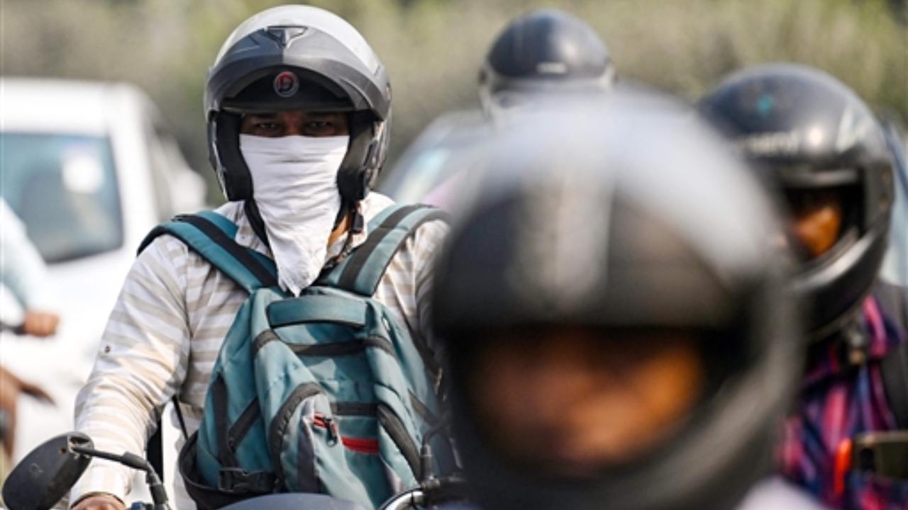 A commuter covers his face with cloth as he rides along a street, amid smoggy conditions in New Delhi