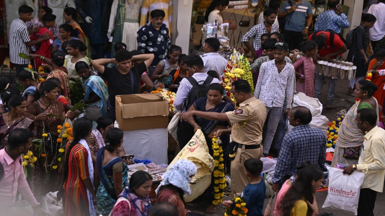A police personnel clears hawkers from the street at Justice MG Ranade Road outside Dadar Station  