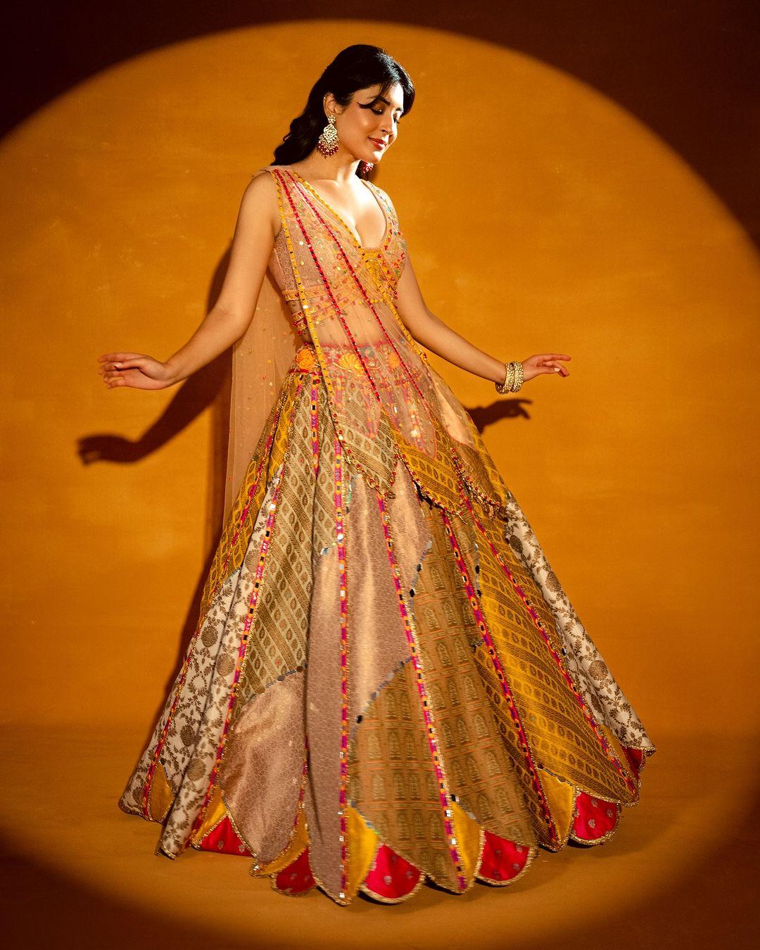 In this look, Kritika wore a beautiful brown lehenga with stunning patchwork on it. The actress paired her lehenga with an embroidered strappy deep-neck yellow blouse along with a see-through dupatta