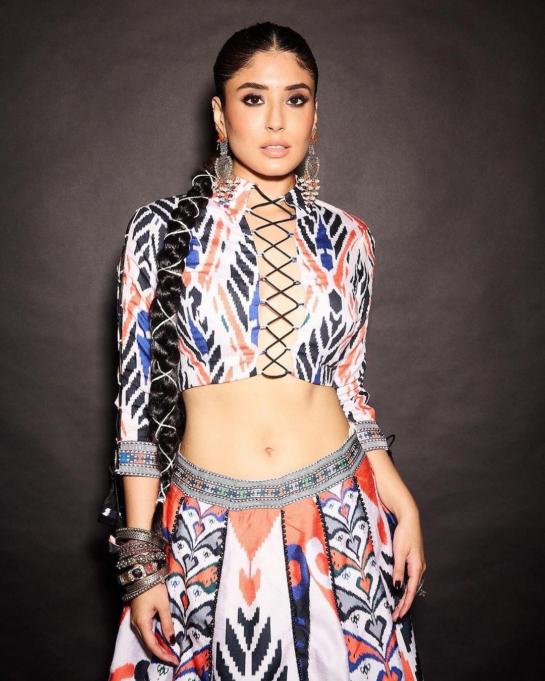In this look, Kritika wore a beautiful white lehenga that features different colored graphics. The actress paired her lehenga with a matching blouse in ikkat print, with coordinating cutwork at the front.