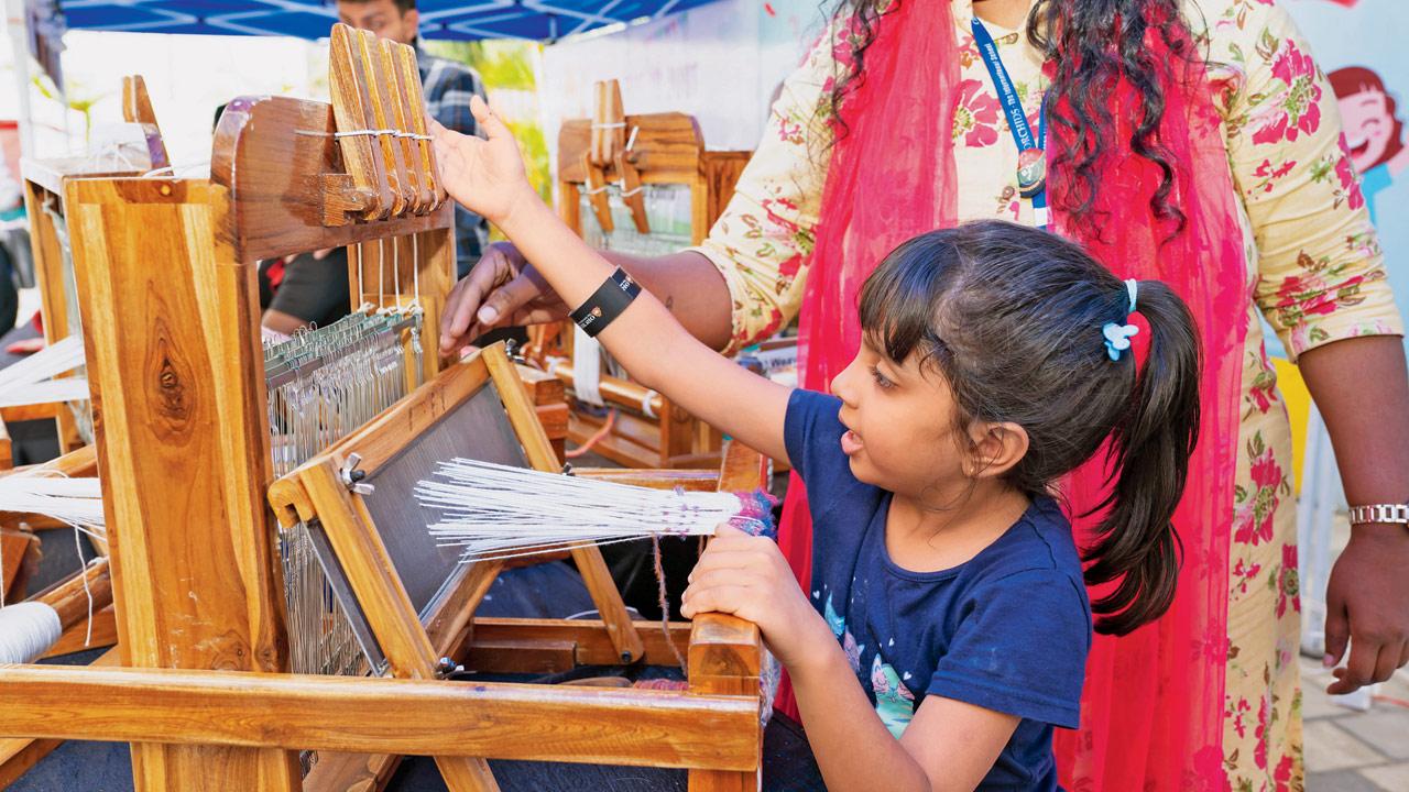 A child tests a weaving loom at an earlier edition