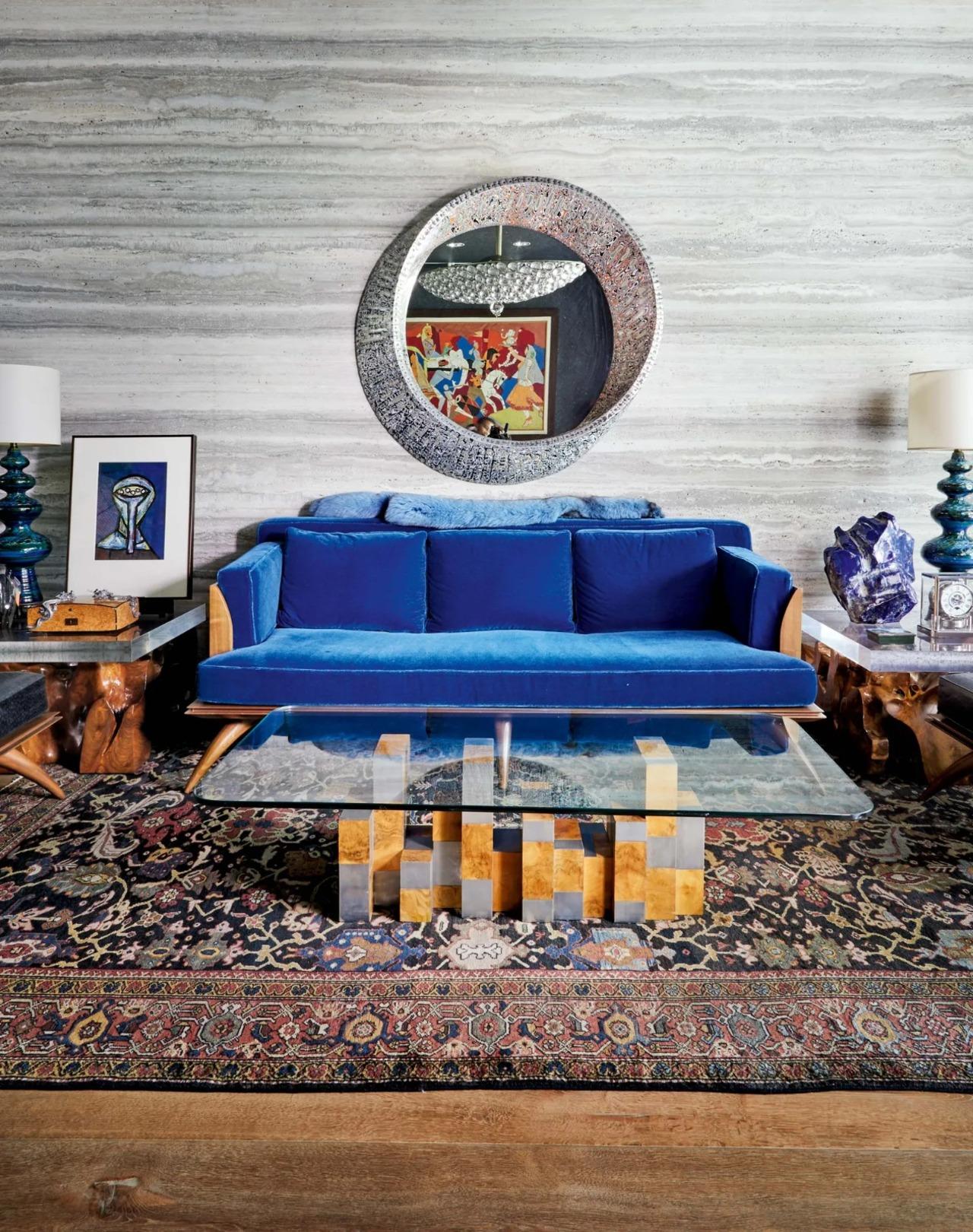 The Paul Mathieu Bianca sofa is at the center of attention in a room that is filled with a antique teak-root table, an enamel-and-metal Roland Mellan mirror on the wall from a New York store and a coffee table by Paul Evans
