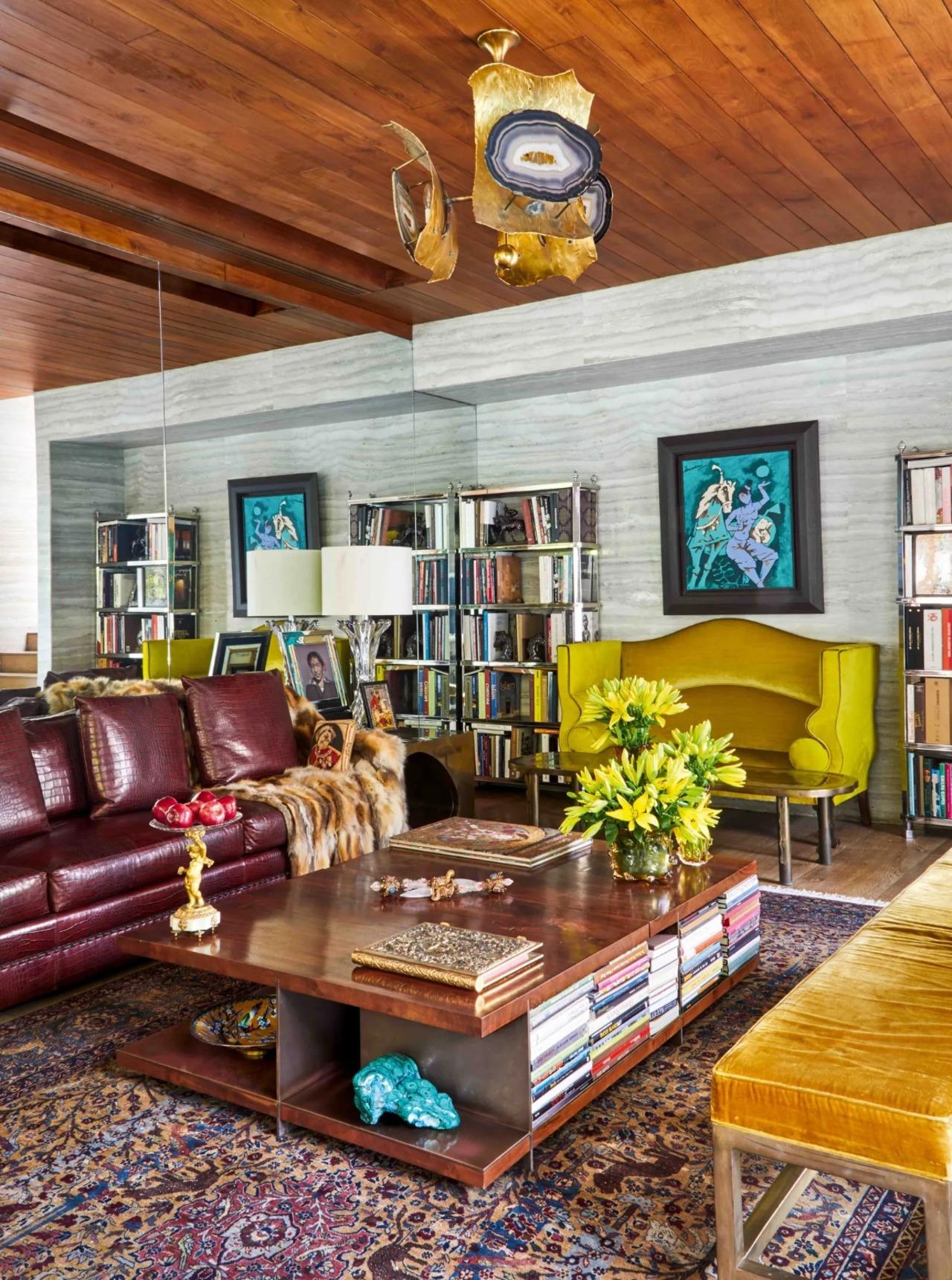 The wall of the living room is adorned by MF Husain. A chandelier hangs above the center table by Hudson Furniture. The lamp on the side table next to the sofa is in Murano glass