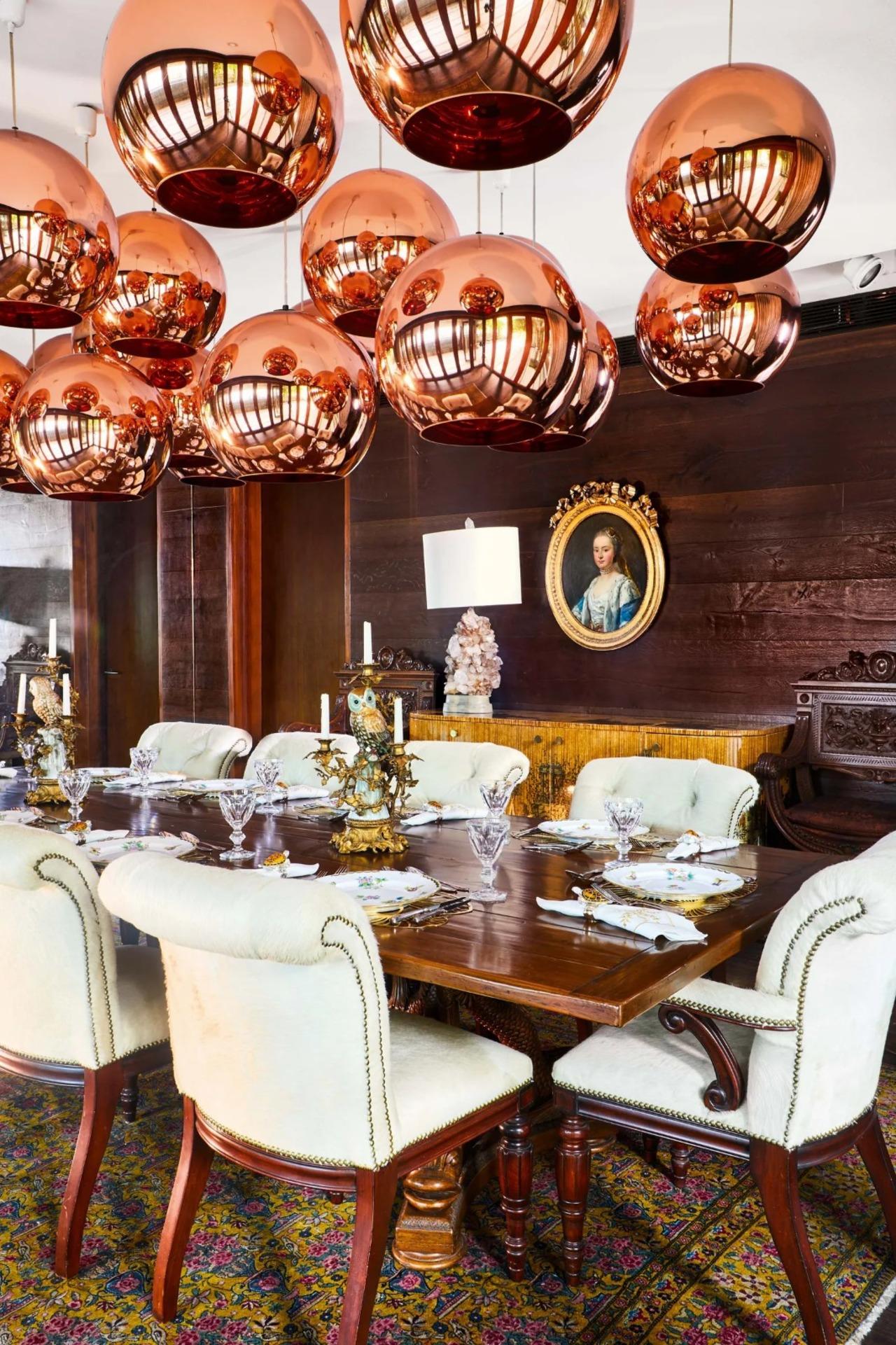 In the formal dining room, the copper pendant light cluster is by Tom Dixon. On the console, beneath the late-18th-century portrait, is a 1970s rock-crystal lamp. The 17th-century French porcelain and gilt bronze candle stand on the dining table is accompanied by Meissen dinnerware