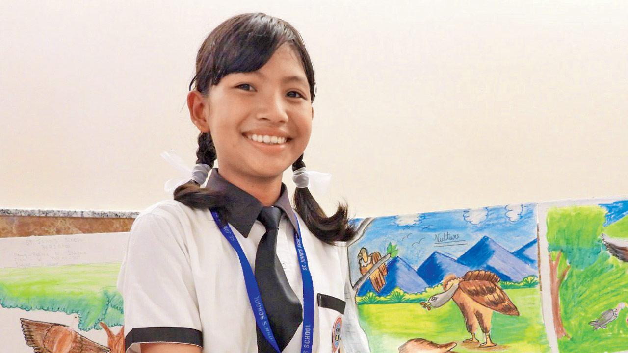 A student holds up her drawings featuring vultures