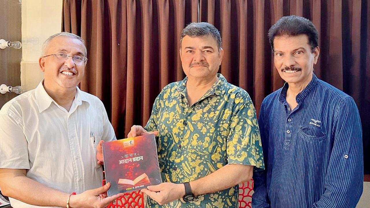 Damle (centre) with Pai (right) hold up the first copy of the edition