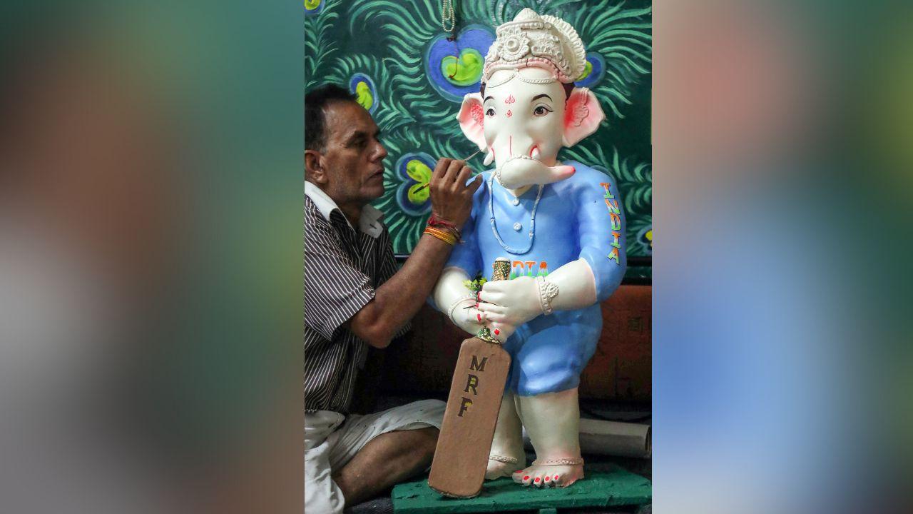 An artist gives a final touch to the idol of Lord Ganesha as an Indian cricketer ahead of Ganesh Chaturthi festival, at a workshop, in Nagpur.