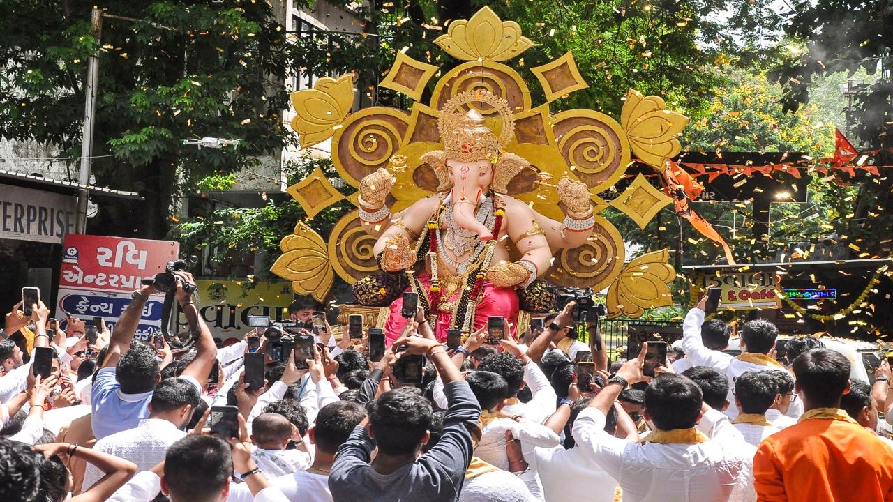 Devotees capture the shots of their favourite deity in their cameras, when it is on its way to a pandal in Surat