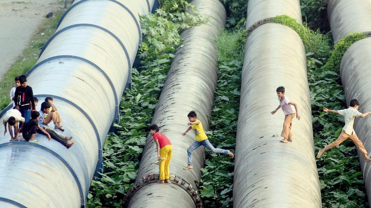 Kids playing on water pipelines in Bandra; civic bodies blame slum clusters for leakages and illegal water connections. Pic/Atul Kamble