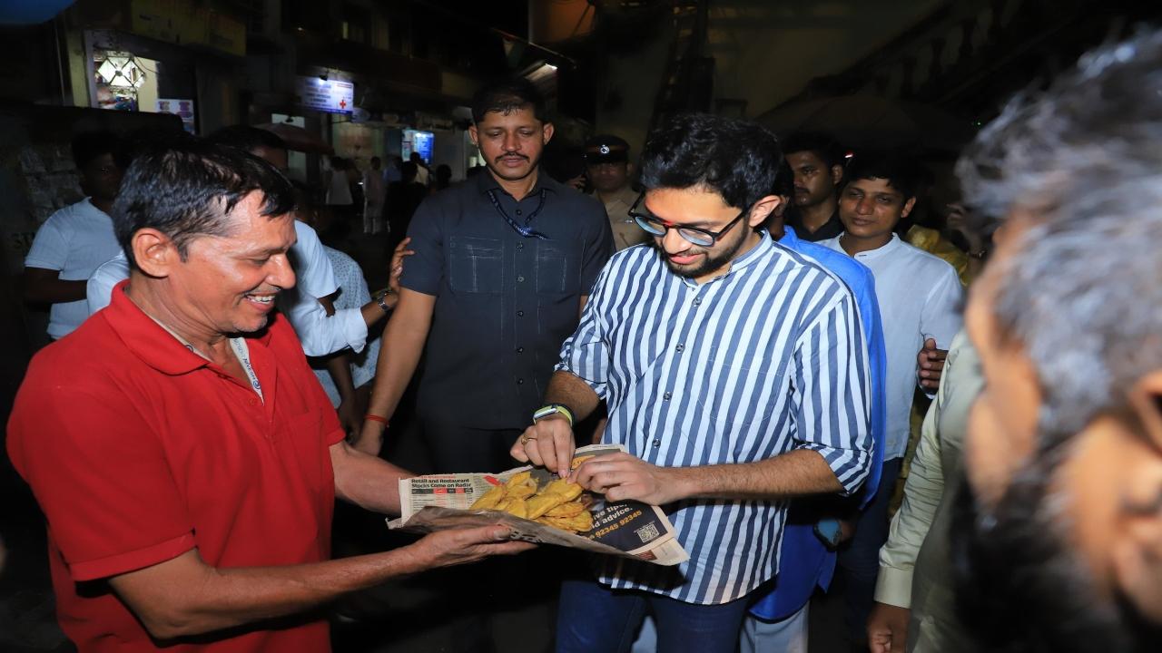 Aaditya Thackeray is offered snacks by a local outside the Worli Koliwada Sarvajanik Ganesh Mandal