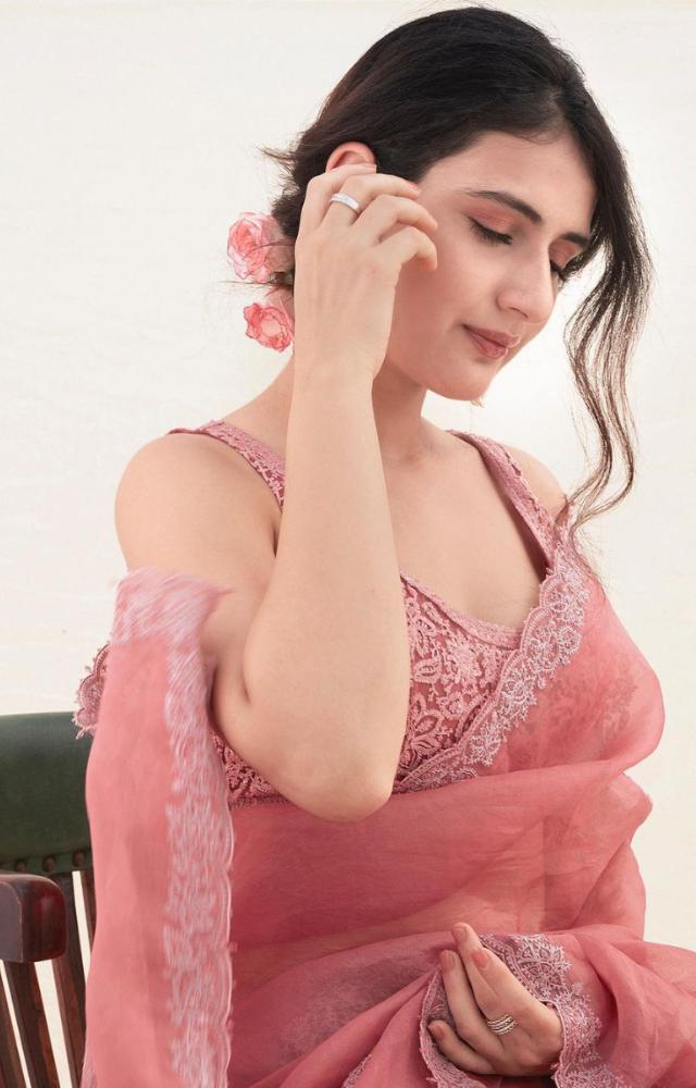 The saree is complemented by a matching pink blouse, which is adorned with intricate silver embroidery that covers it entirely, creating a stunning contrast