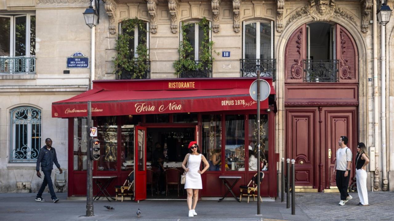 A woman wearing a red beret poses for photographs next to the restaurant 'Terra Nera'