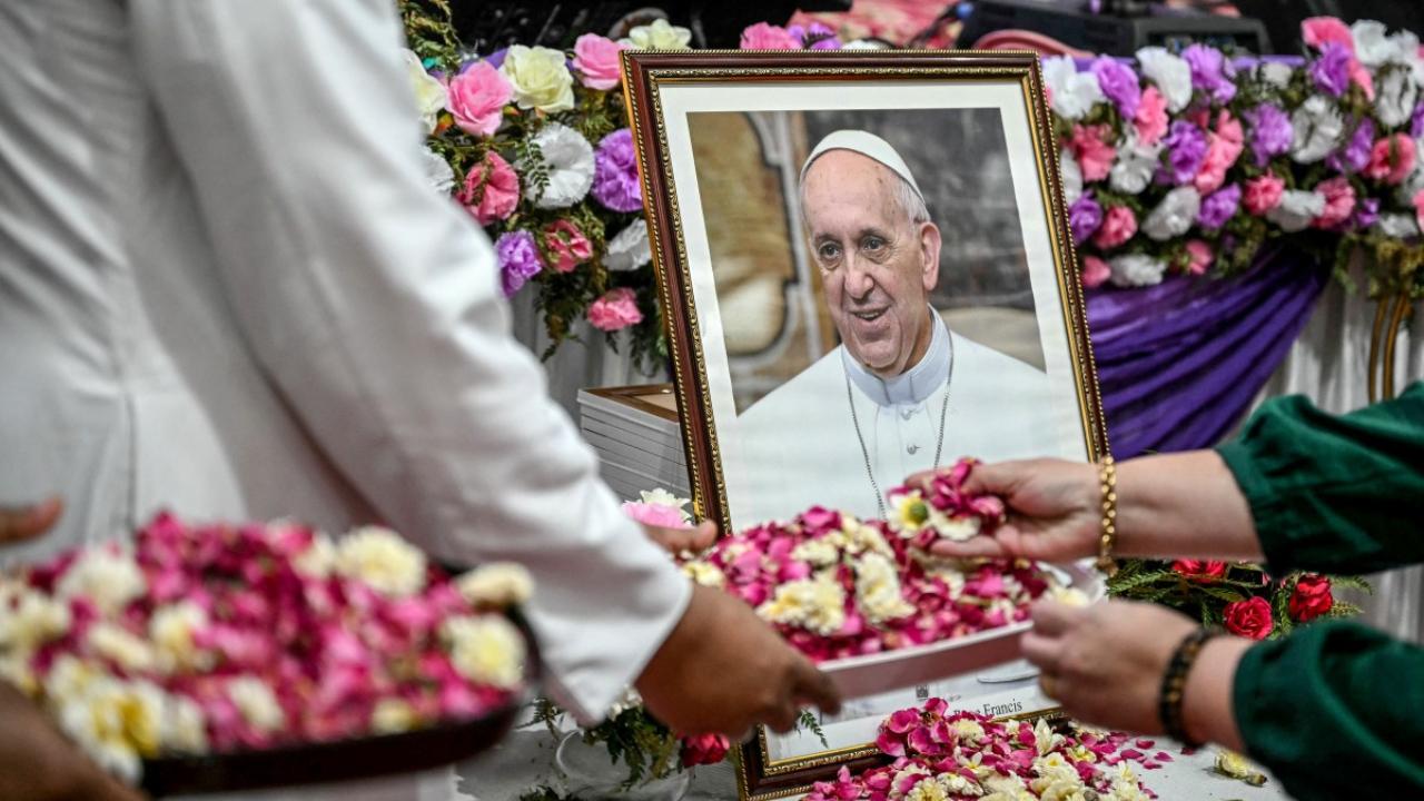 People showered flower petals as they paid respects in front of a portrait of Pope Francis during a condolence meeting in New Delhi, India