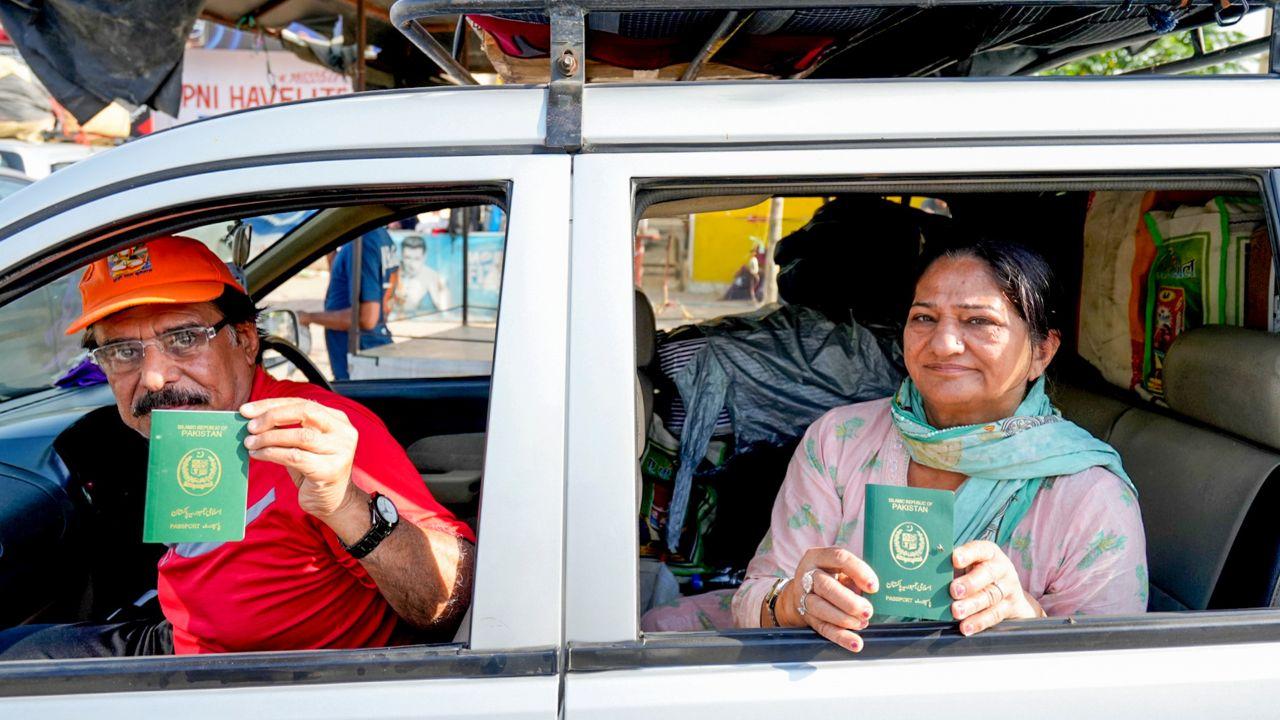 Pakistani nationals show their passports as they wait for clearance to cross the border at the Integrated Check Post at the Attari-Wagah border