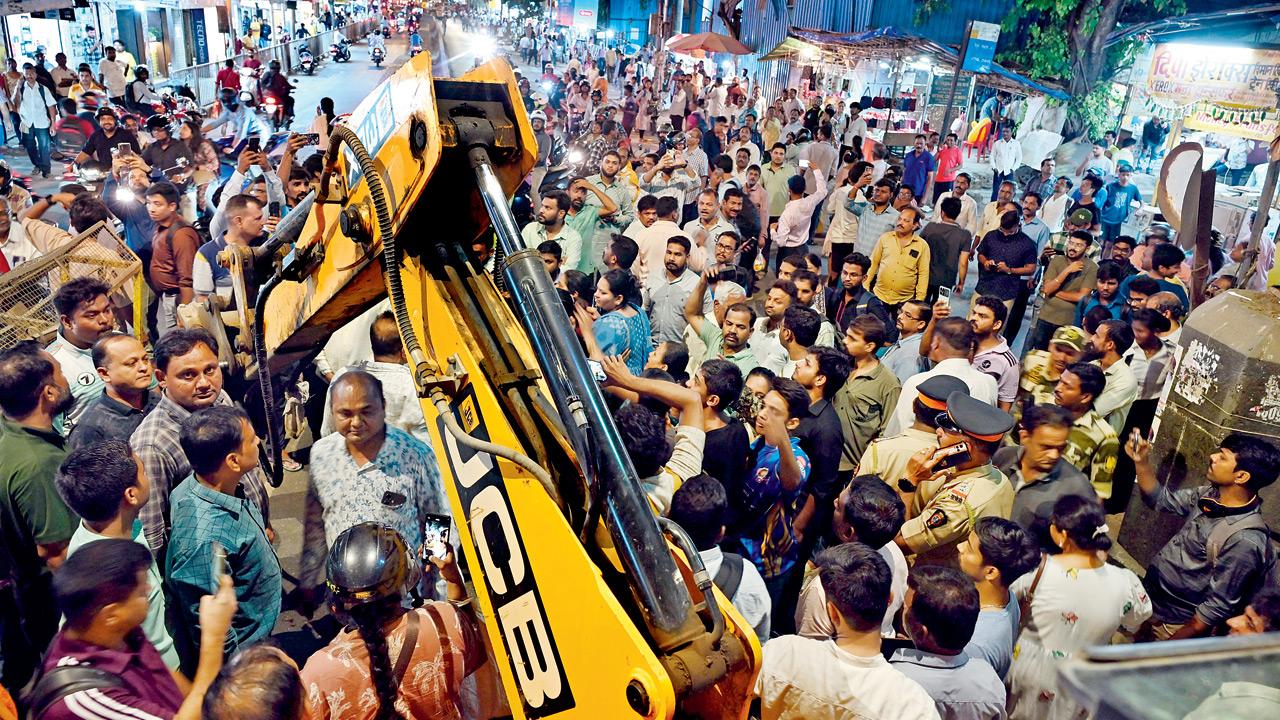 Locals stop the JCB brought by the authorities for demolition. Pics/Atul Kamble