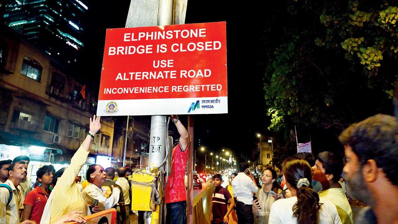 Protesting residents pull down the bridge closure banner put up by the authorities. Pic/Atul Kamble