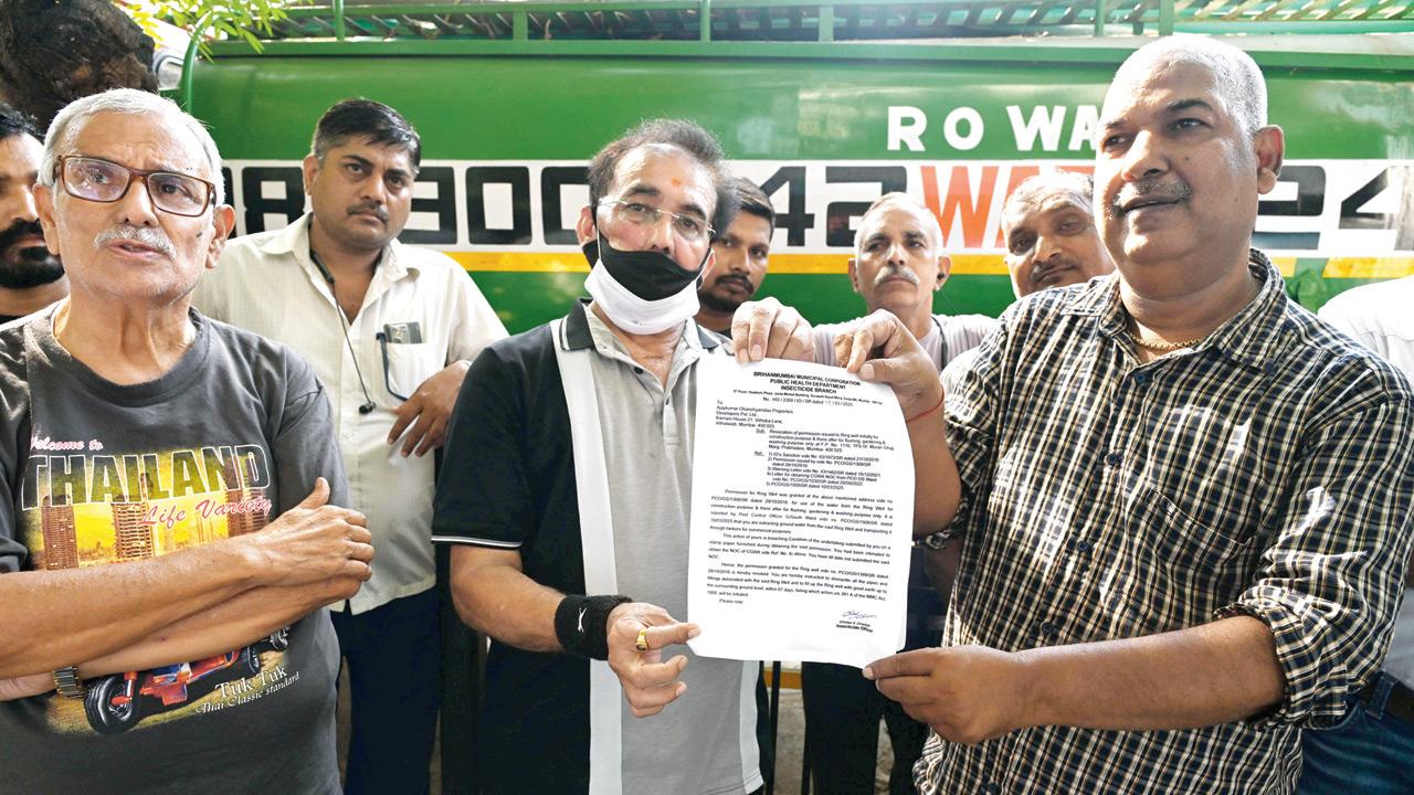 Santosh Singh (right), coordinator of Dadar and Prabhadevi tankers with other tanker owners hold the BMC notice issued to well owners 
