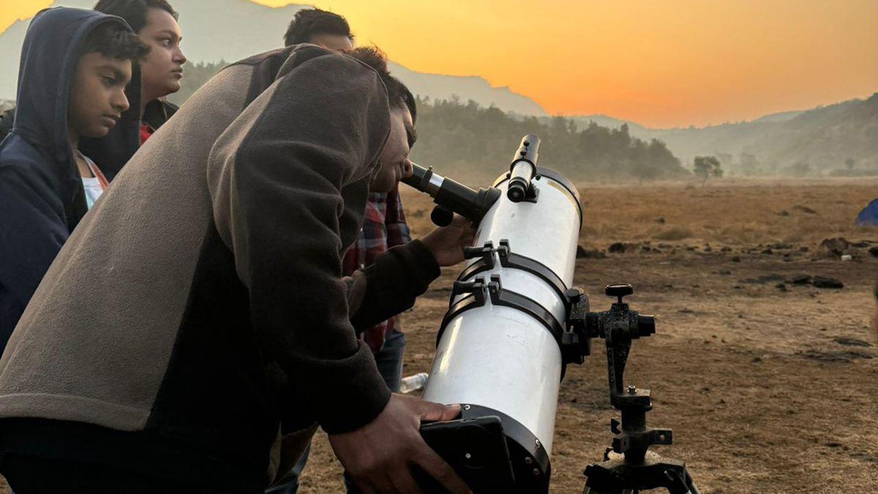 Participants use a telescope to see celestial bodies at a previous stargazing camp 