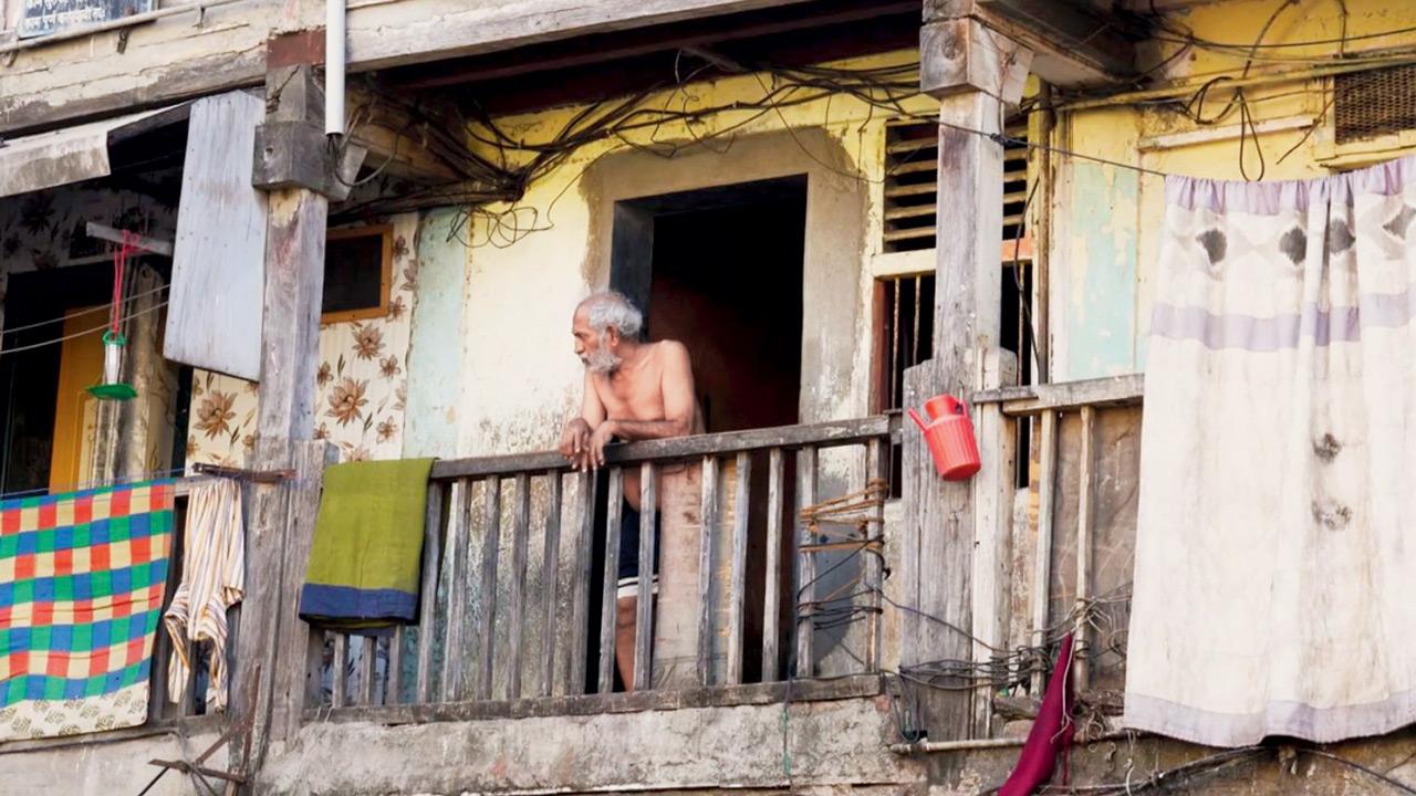 An old man looks out from the balcony of a chawl in the area