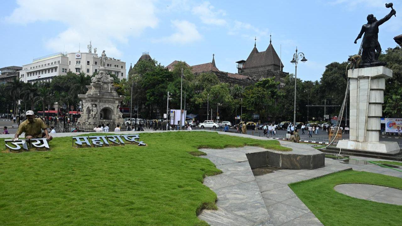 The site features a neatly maintained lawn, an eternal flame, and a green patch shaped like the state of Maharashtra