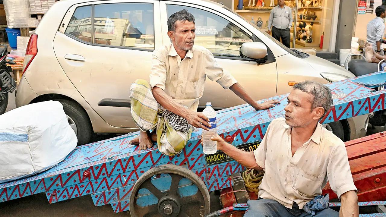 Handcart workers hydrate themselves at Abdul Rehman Street as temperatures soar.