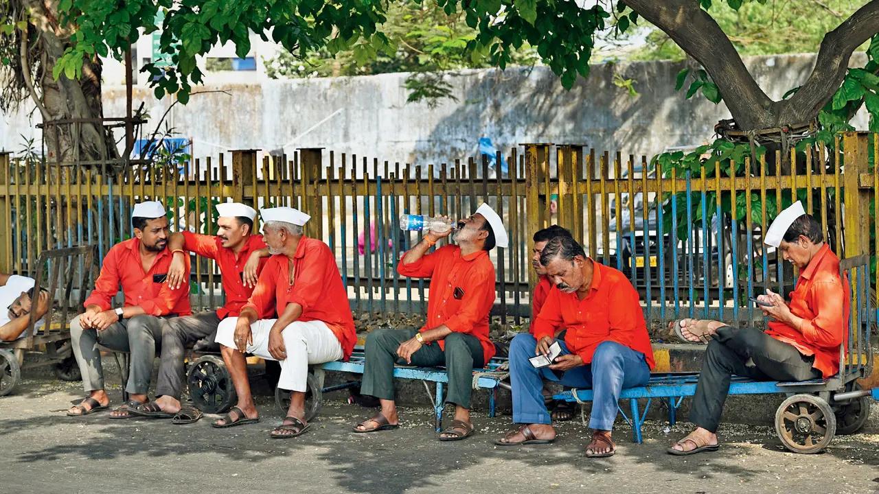 At Bandra Terminus, railway porters huddle in shade, attempting to escape the worst of the afternoon heat.