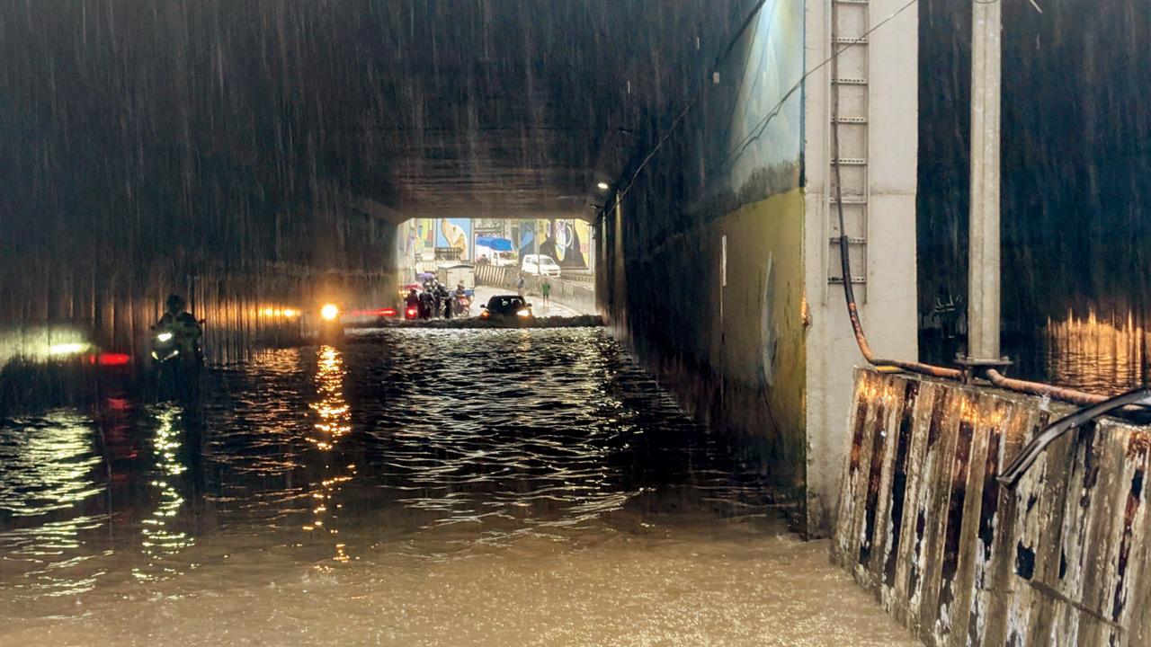 Despite warnings, two-wheeler riders risk crossing the waterlogged Aarey underpass. Pics/By Special Arrangement