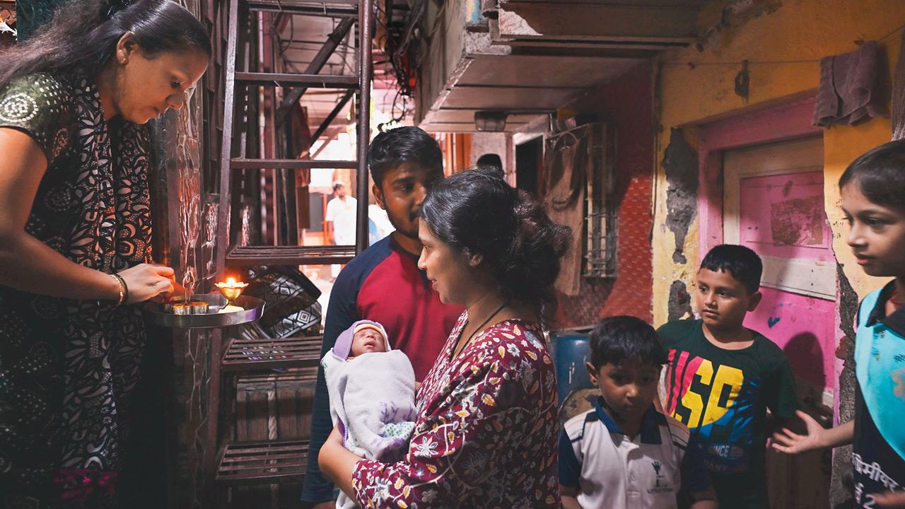 A relative of the Mores performs an aarti to welcome Baby More home
