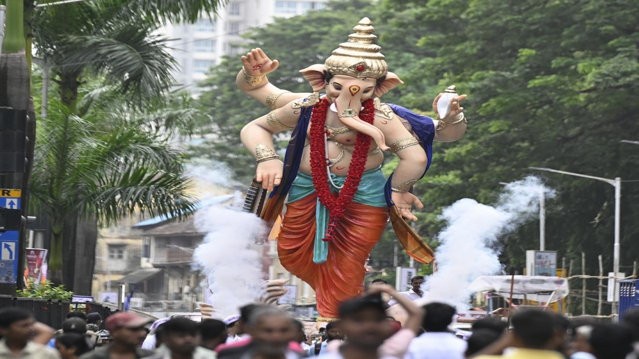 Devotees burst crackers as an idol is being taken to a Parel pandal