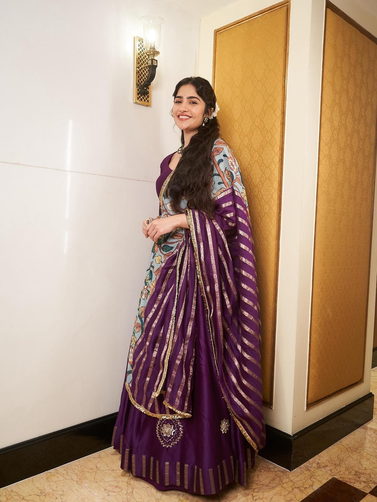 Rukmini Vasanth looks elegant in this traditional ensemble. She is dressed in a deep purple lehenga adorned with gold detailing, paired with a floral and striped dupatta.