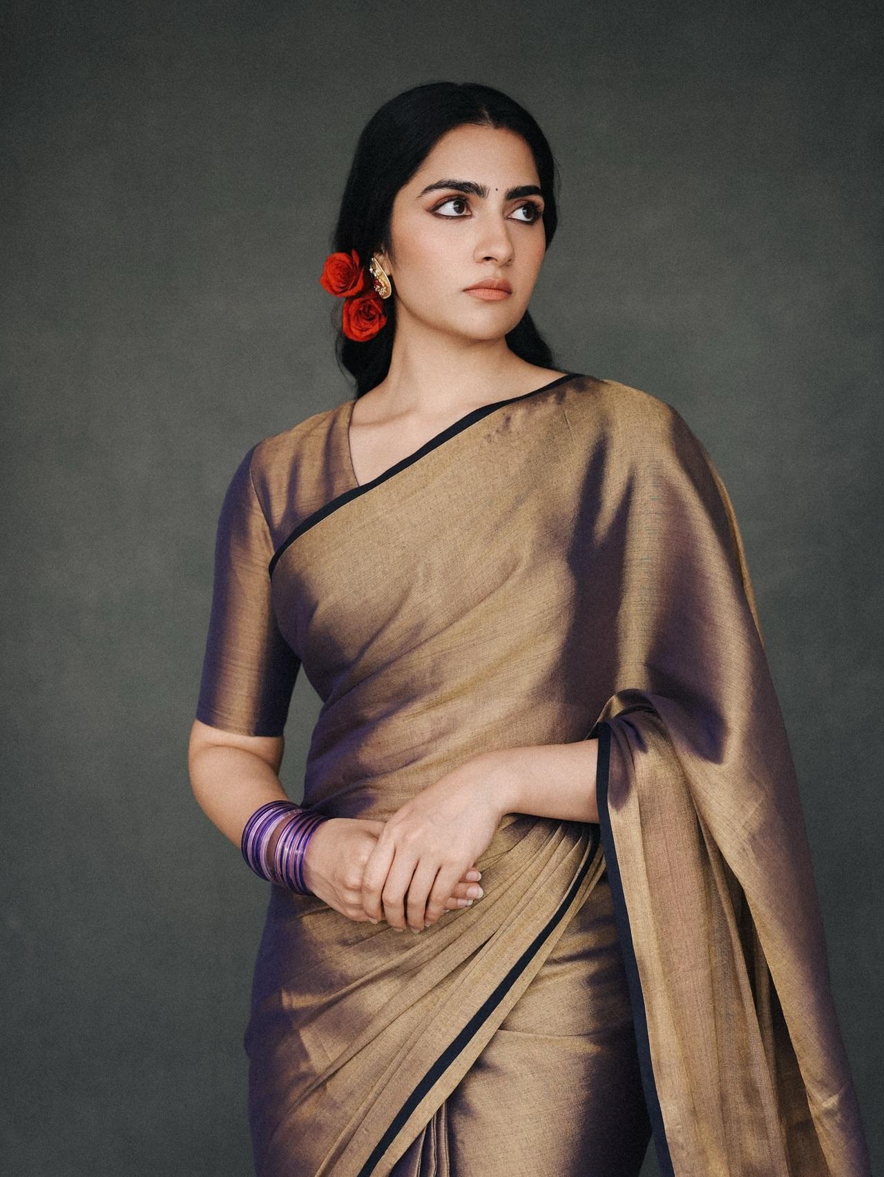 The earthy tones of the bronze mushroom-silk saree give this look a quietly romantic, evening-ready vibe. Rukmini pairs it with red roses in her hair — a detail that adds softness and femininity.