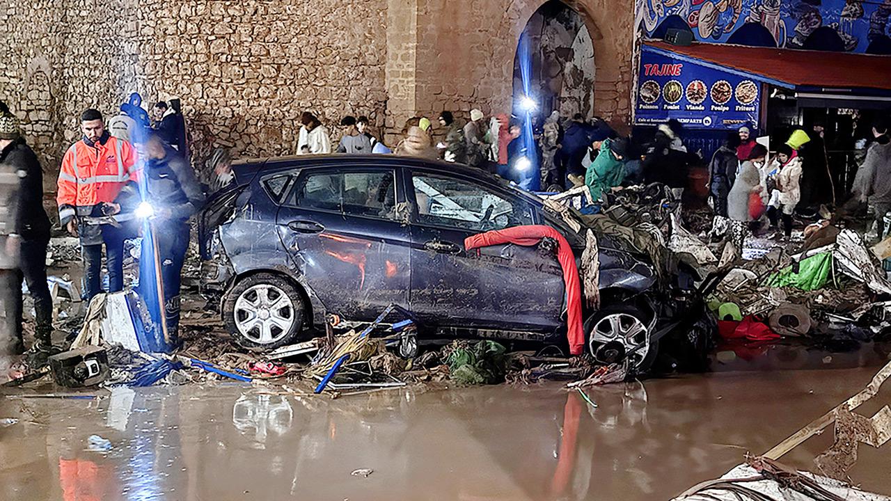 People walk past debris left by the flood, on Sunday. Pic/Getty Images