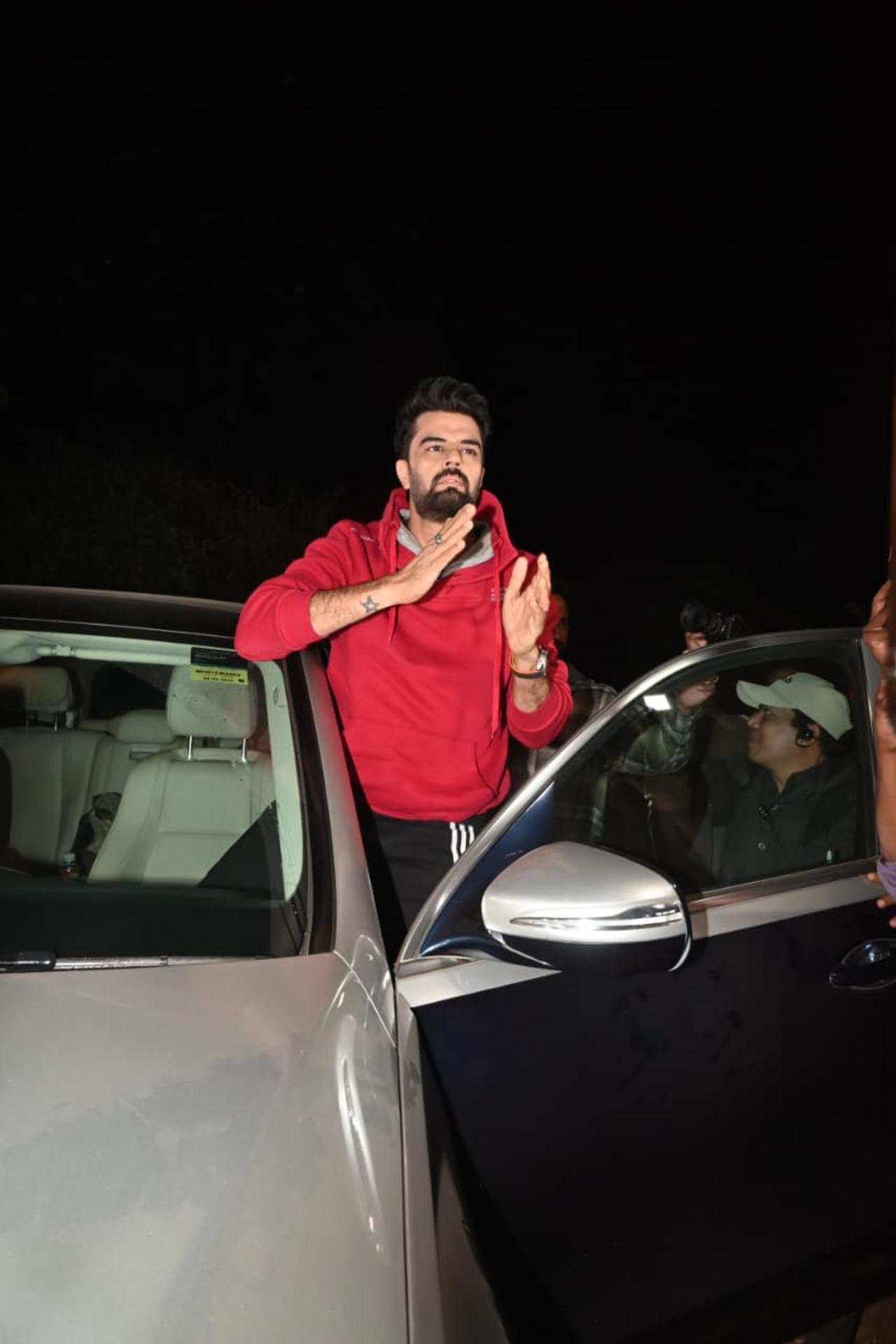 Maniesh Malhotra greets the paps as he reaches at the farmhouse in a red hoody