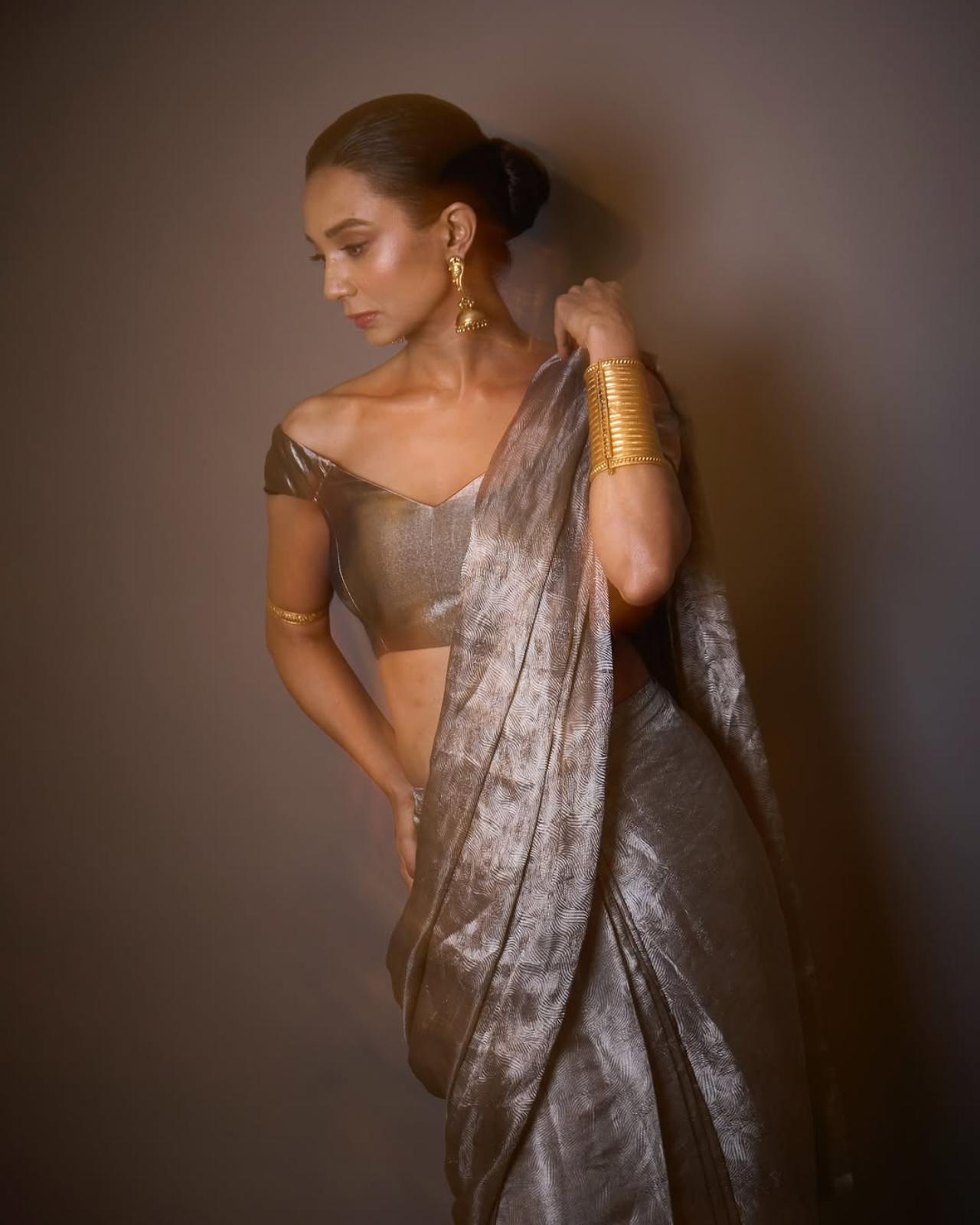In this look, Dubey opts for a unique metallic-finish saree. The matching off-shoulder blouse complements the saree, and the ornate earrings and gold cuff bracelet complete the look. 