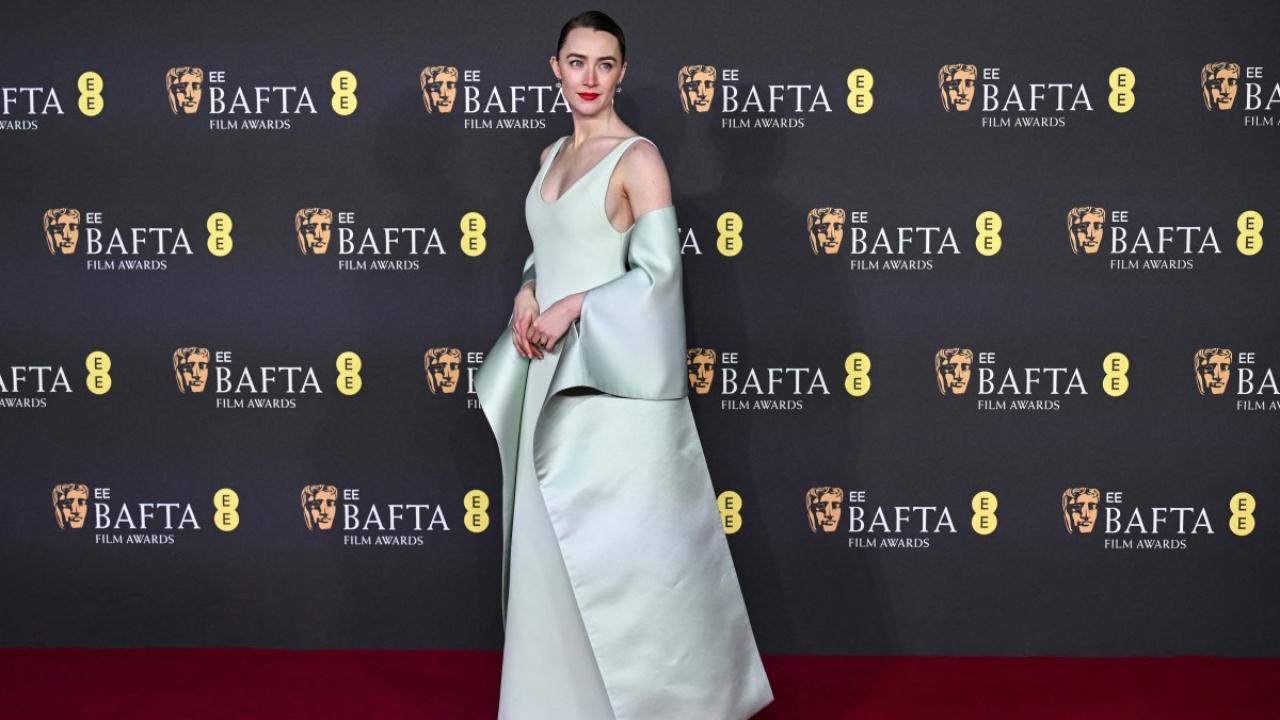 Saoirse Ronan aced an elegant satin aquamarine gown by Louis Vuitton. The slicked-back hairstyle and bold red lipstick completed the look.