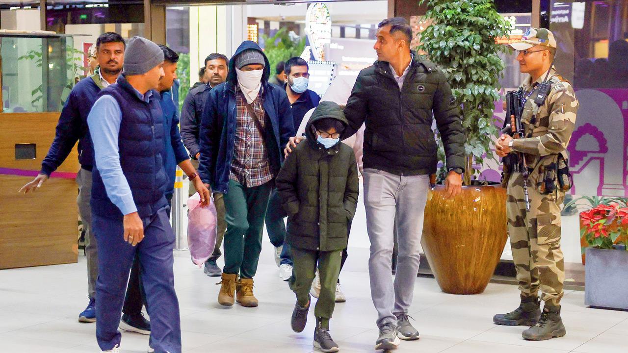 Security personnel escort Gujarat natives deported from US after they were brought to the Ahmedabad airport. Pic/PTI